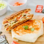 vegetarian crunchwrap cross-section on top of uncut crunchwrap with Taco Bell hot sauce packets