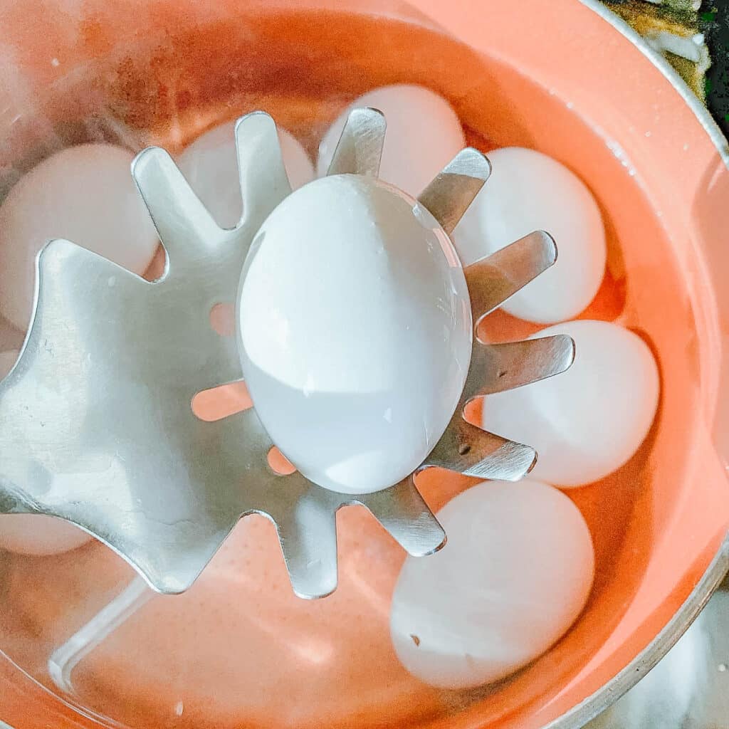 egg being lifted from pot full of eggs on slotted spoon