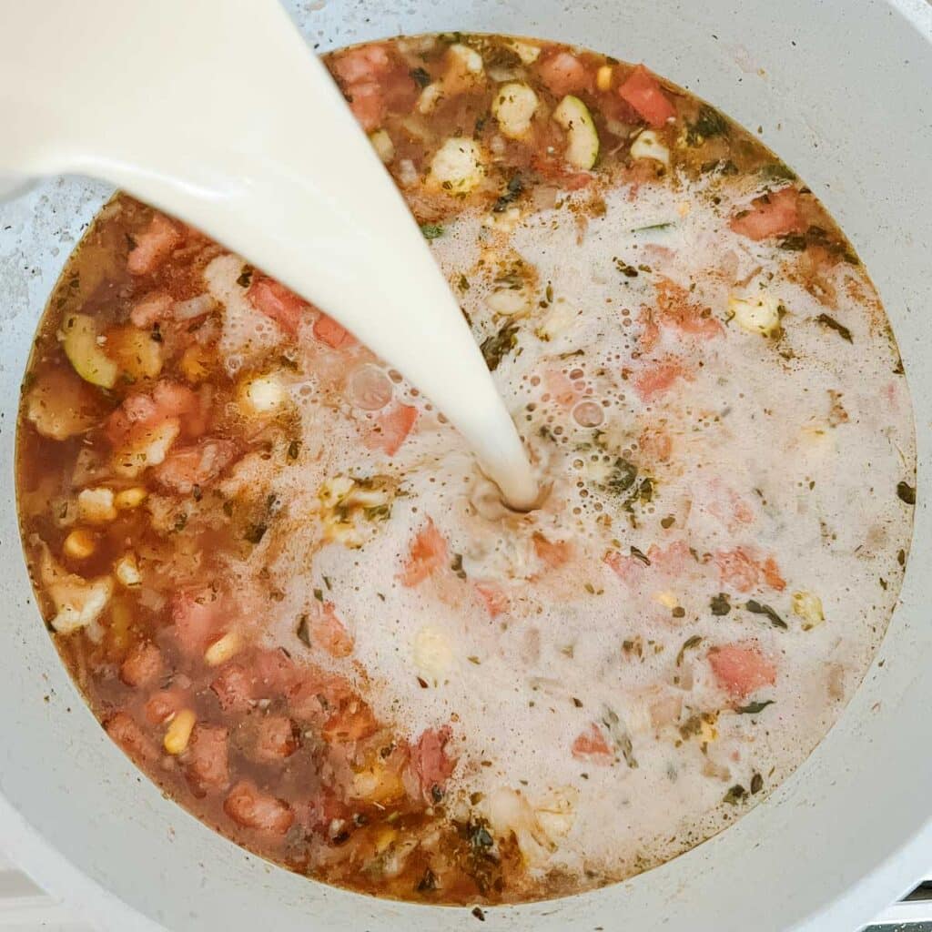 cashew cream being poured into 10 vegetable soup