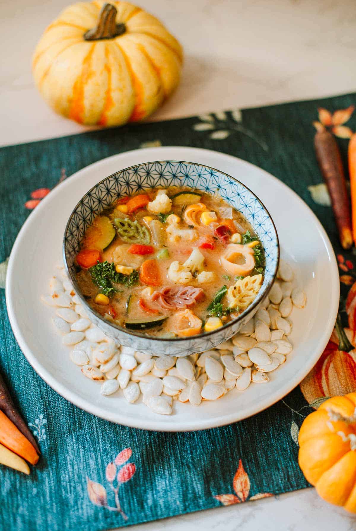 10 vegetable soup on plate with pumpkin seeds on placemat with pumpkins