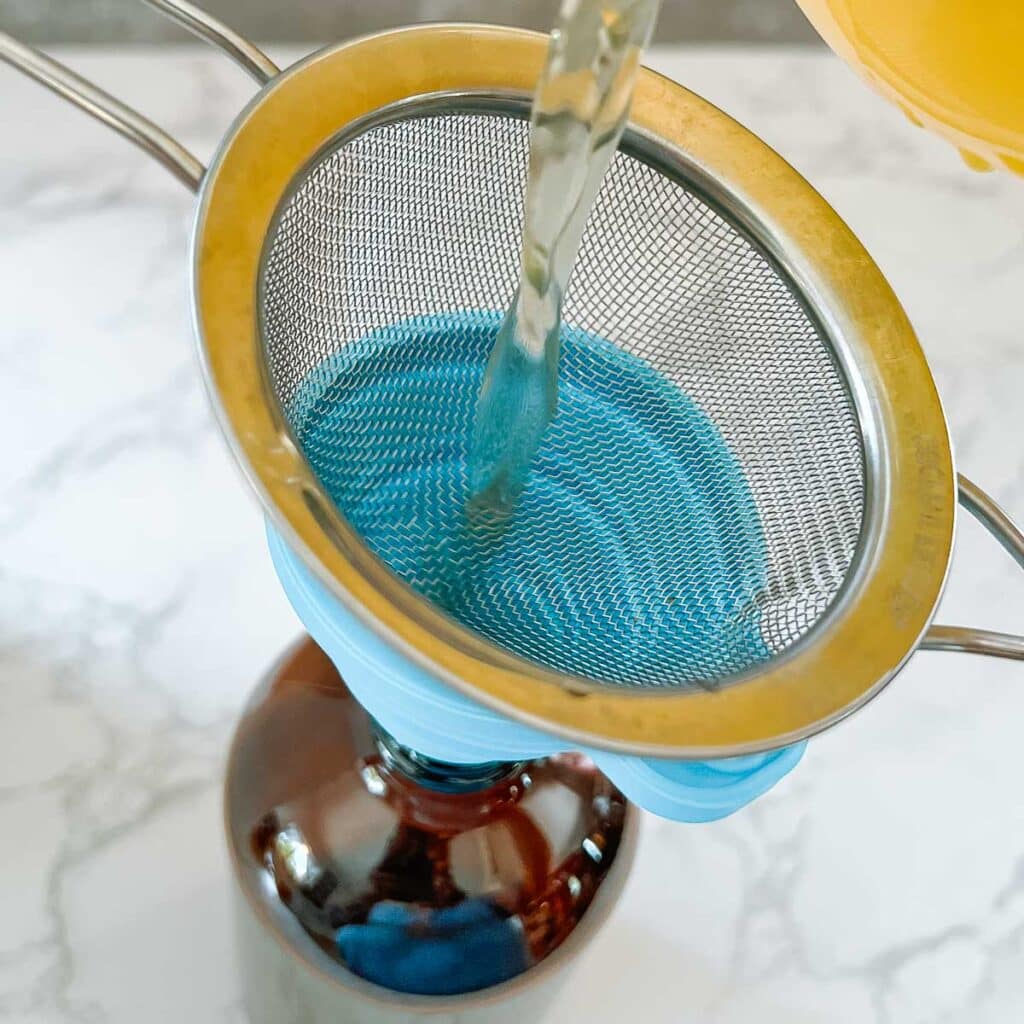 pouring liquid through strainer into funnel