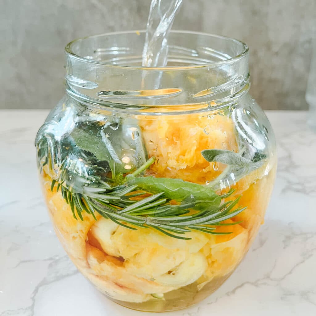 pouring vinegar into jar of orange peels