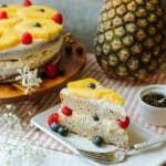 pineaplle cream cheese frosting cake slice on plate with cake, jasmine tea leaves, and whole pineapple in background