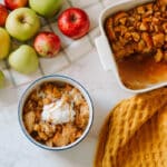 condensed milk bread pudding in a pan with a portion in a bowl with ice cream beside fresh apples.