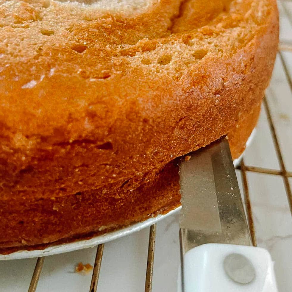 cake being cut into two layers with a bread knife.