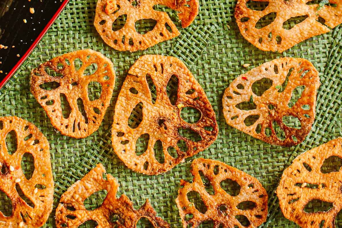 golden lotus root chips spread out on placemat and topped with furikake.