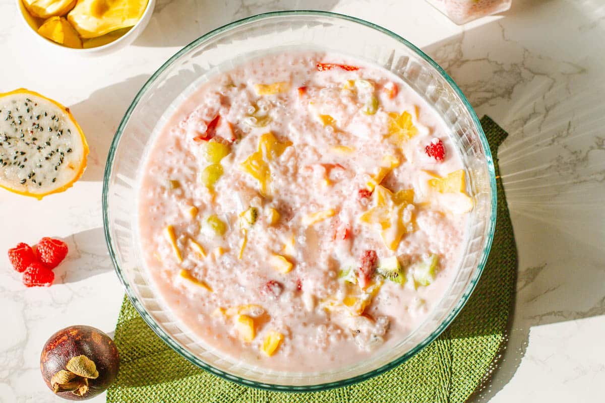 coconut milk sago all mixed with fresh fruits surrounded by jackfruit, dragon fruit, berries, mangosteen.